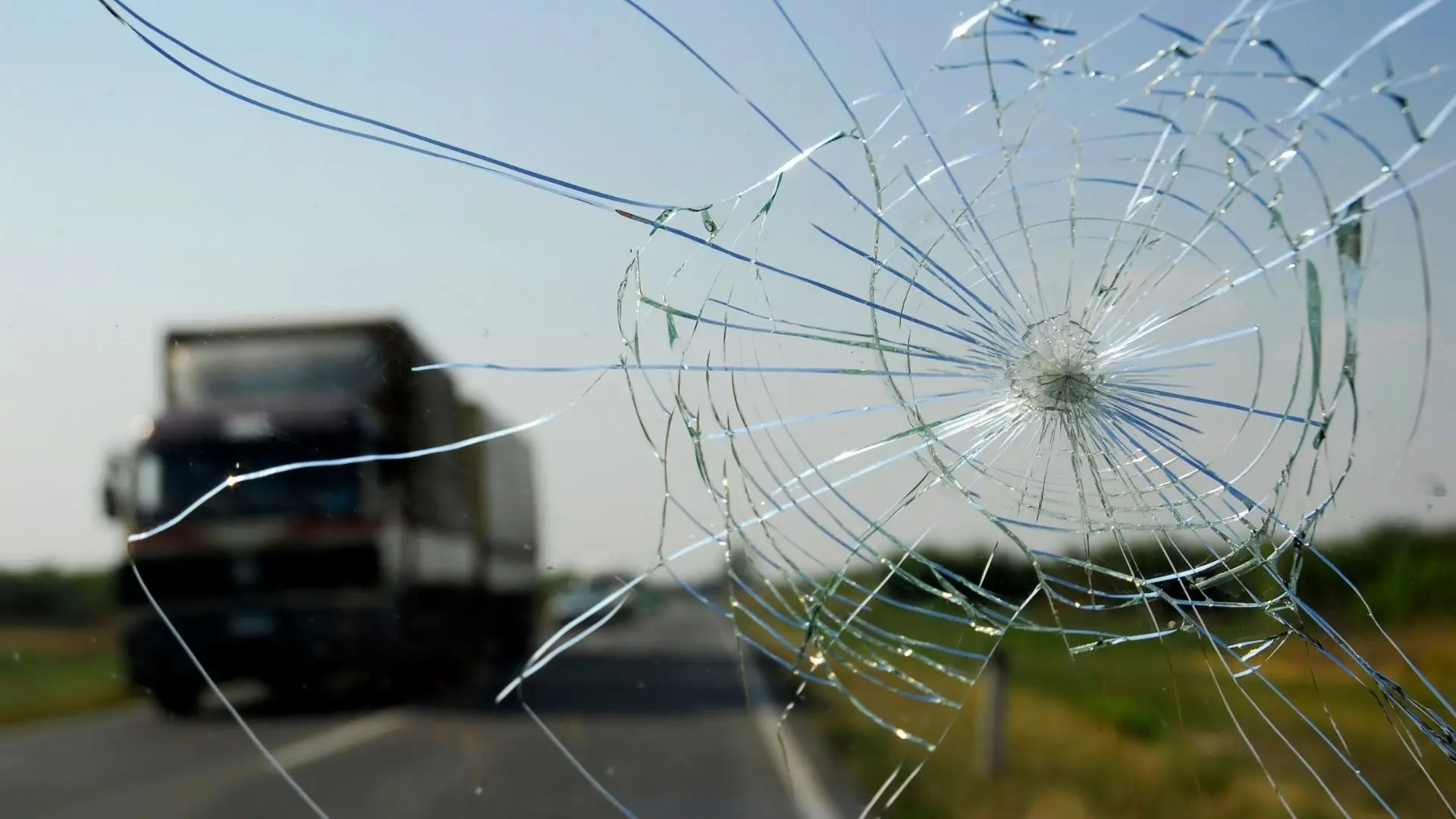 Broken car windshield with the road visible through the cracks